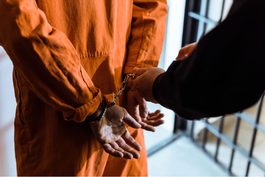 Prisoner in handcuffs and jumpsuit getting transported